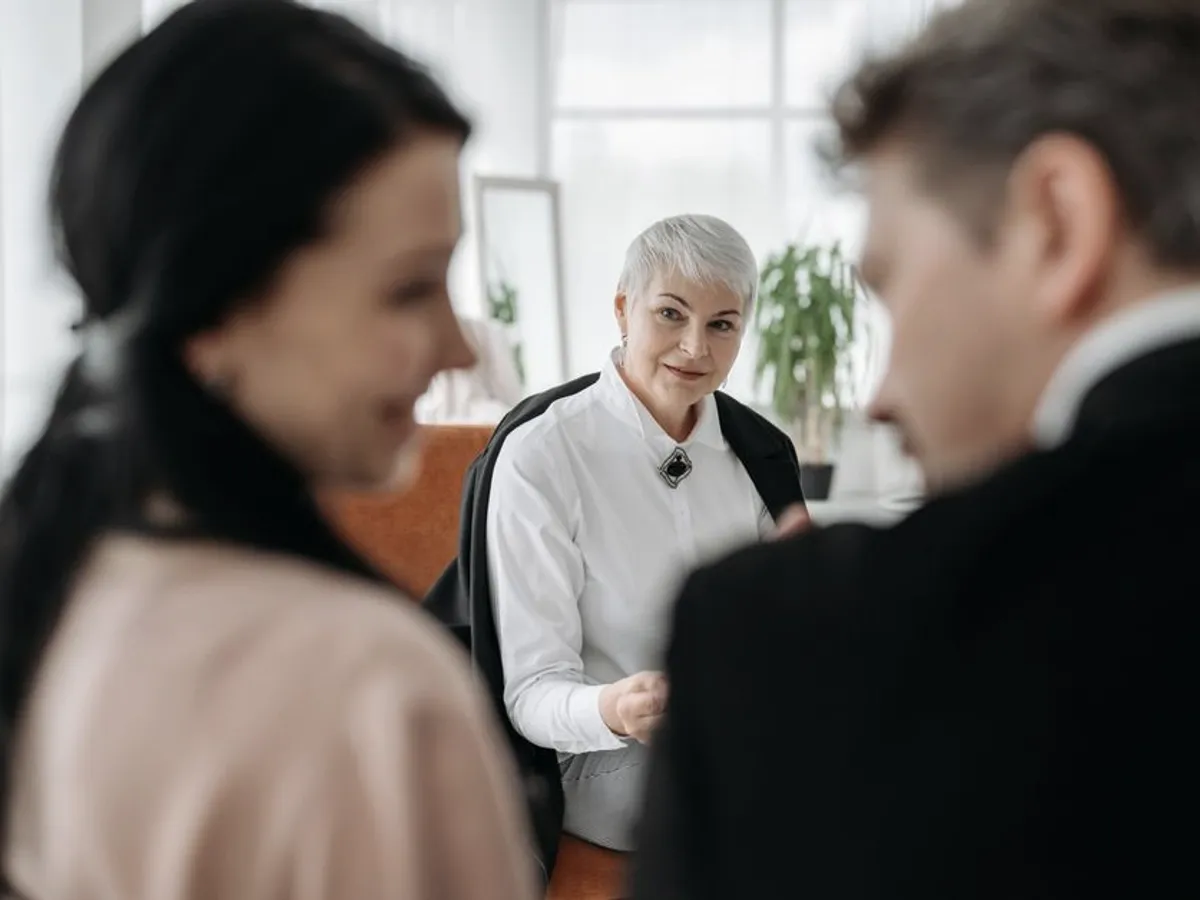 Consultora senior escuchando con atención a sus clientes en una oficina luminosa
