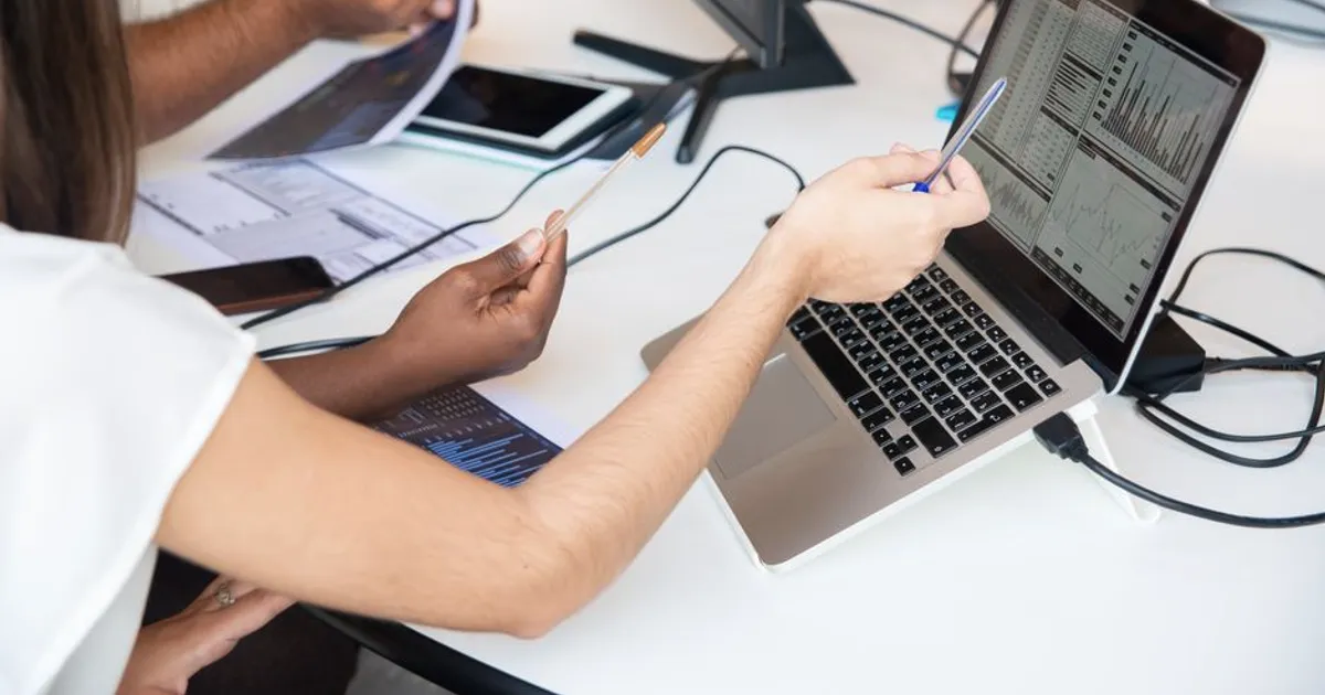 Profesionales analizando gráficos de datos en una laptop, discutiendo en equipo
